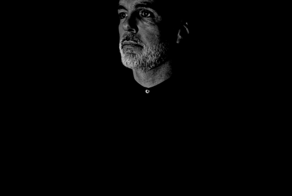 Man with a contemplative expression in a dark, minimalistic portrait symbolizing structure, order, and inner mastery